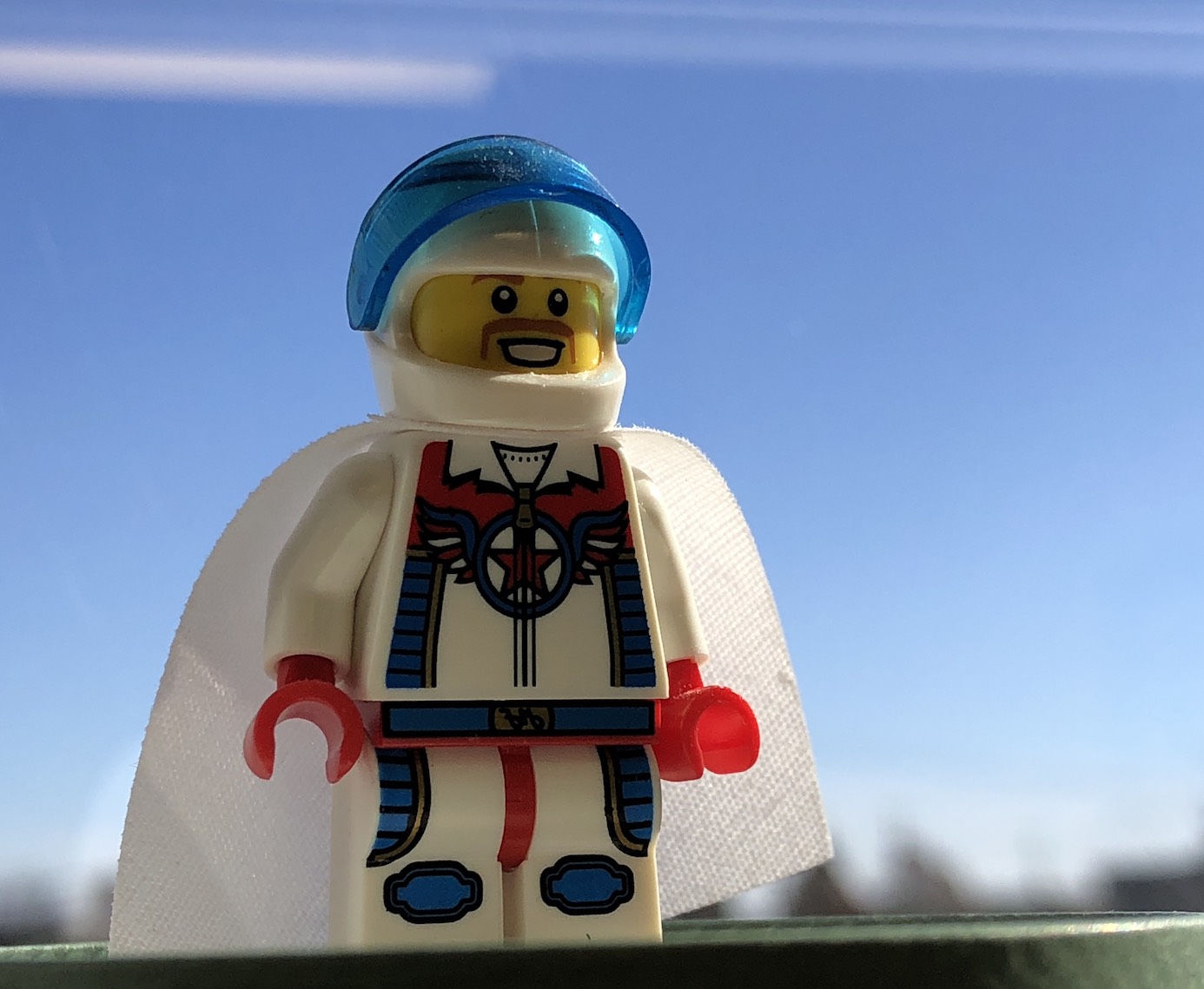 Lego mustachioed daredevil minifigure in a white jumpsuit with blue details and striping against a blue sky.